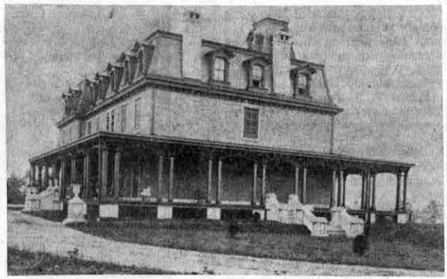 View of original Louella House, home of the Henry Askin family, which was completed in 1869 after having been under construction for one year. This picture shows the west side of the building, with a partial view of the grounds on the east side. The elevation to the right in the picture contains the gas retorts that supplied the building. (A man is shown standing at the entrance to this underground chamber.)